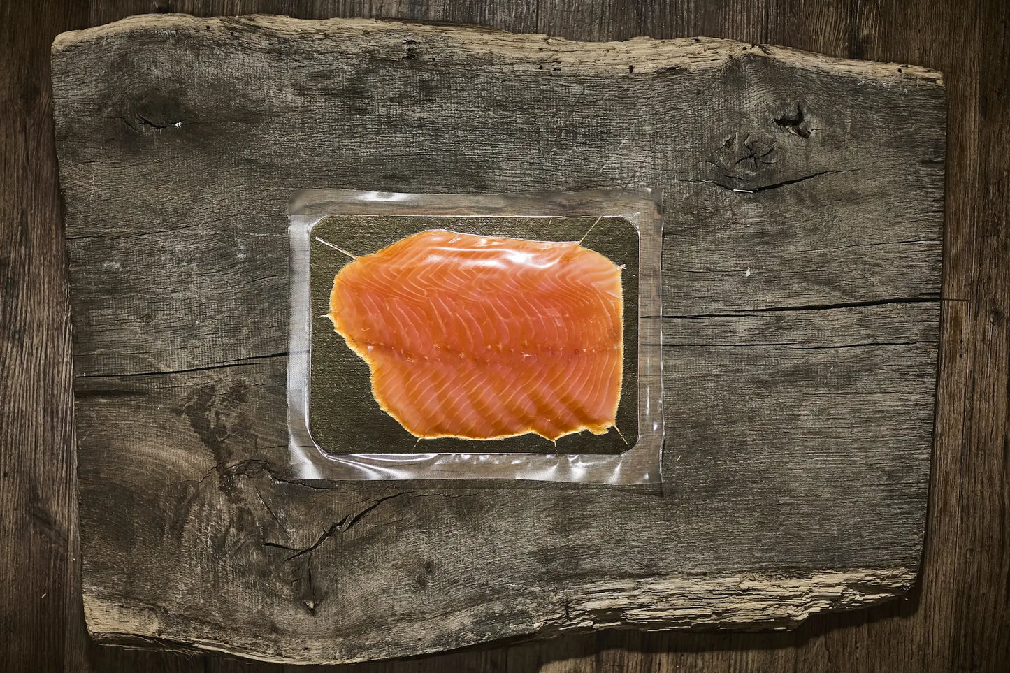 200 g Verpackung vom Räucherlachs auf einer golden platte. Lachs liegt auf einem brauen Holzbrett 