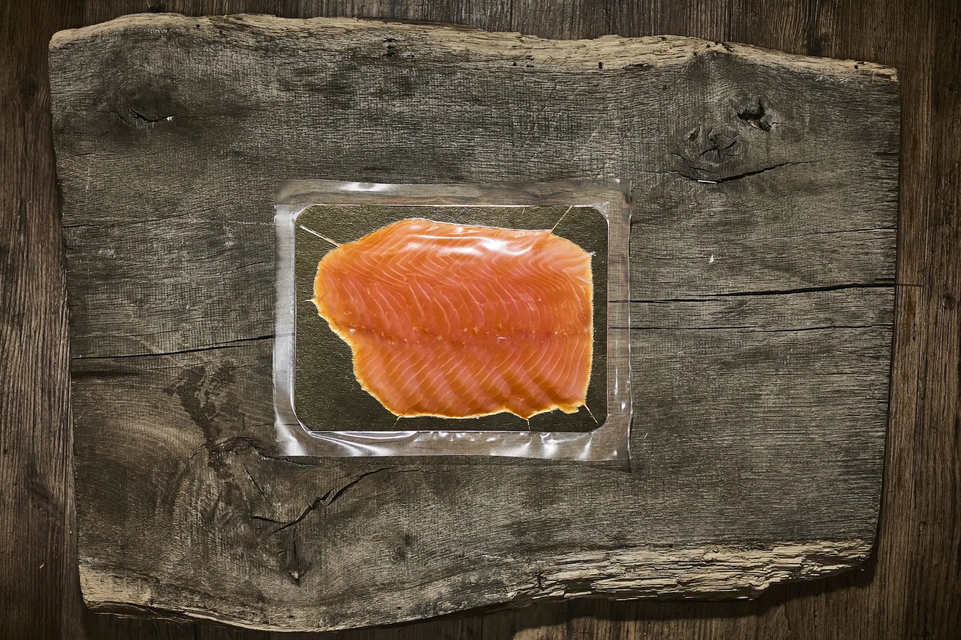 200 g Verpackung vom Räucherlachs auf einer golden platte. Lachs liegt auf einem brauen Holzbrett 